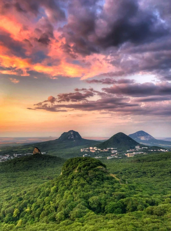 the setting sun is over the mountains with hills and fields