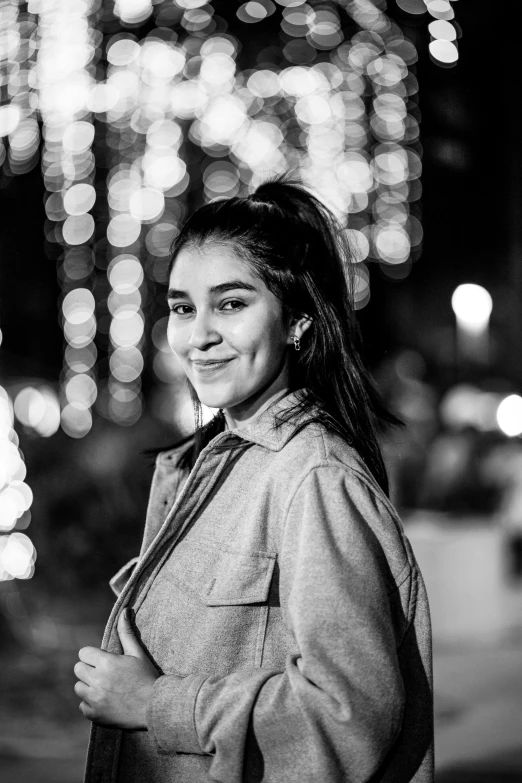 black and white pograph of smiling woman in front of brightly lit background