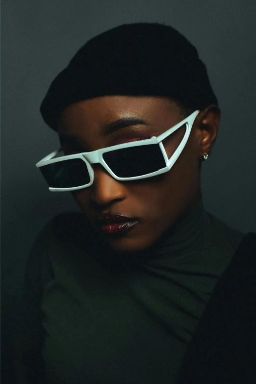 a girl wearing glasses is pographed against a dark backdrop