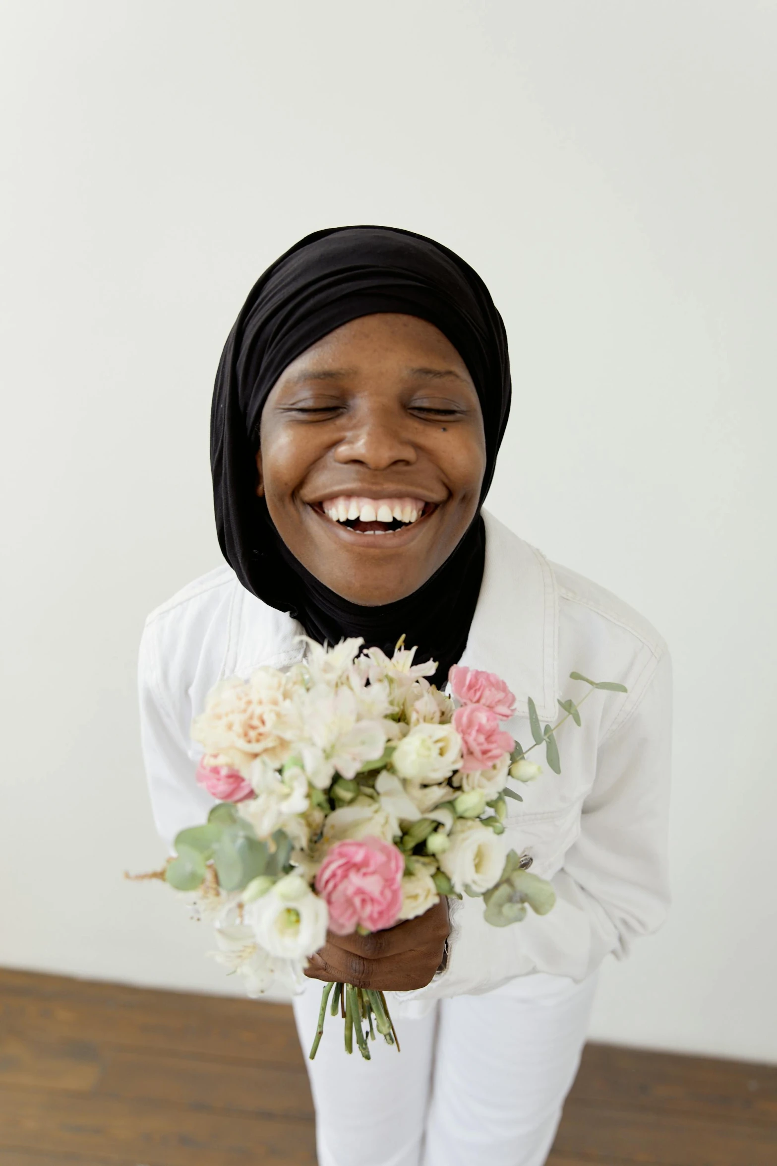 a woman smiles as she holds a bouquet of flowers