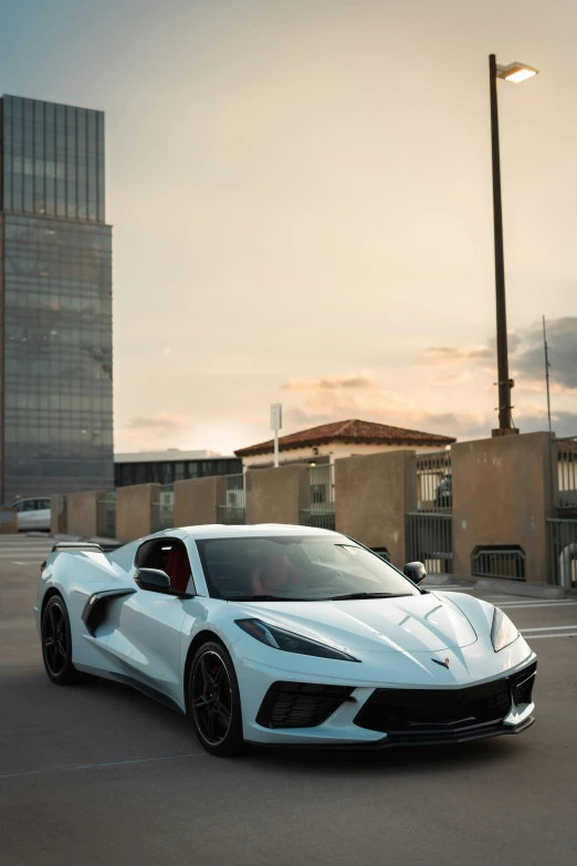 a white sports car driving down a parking lot