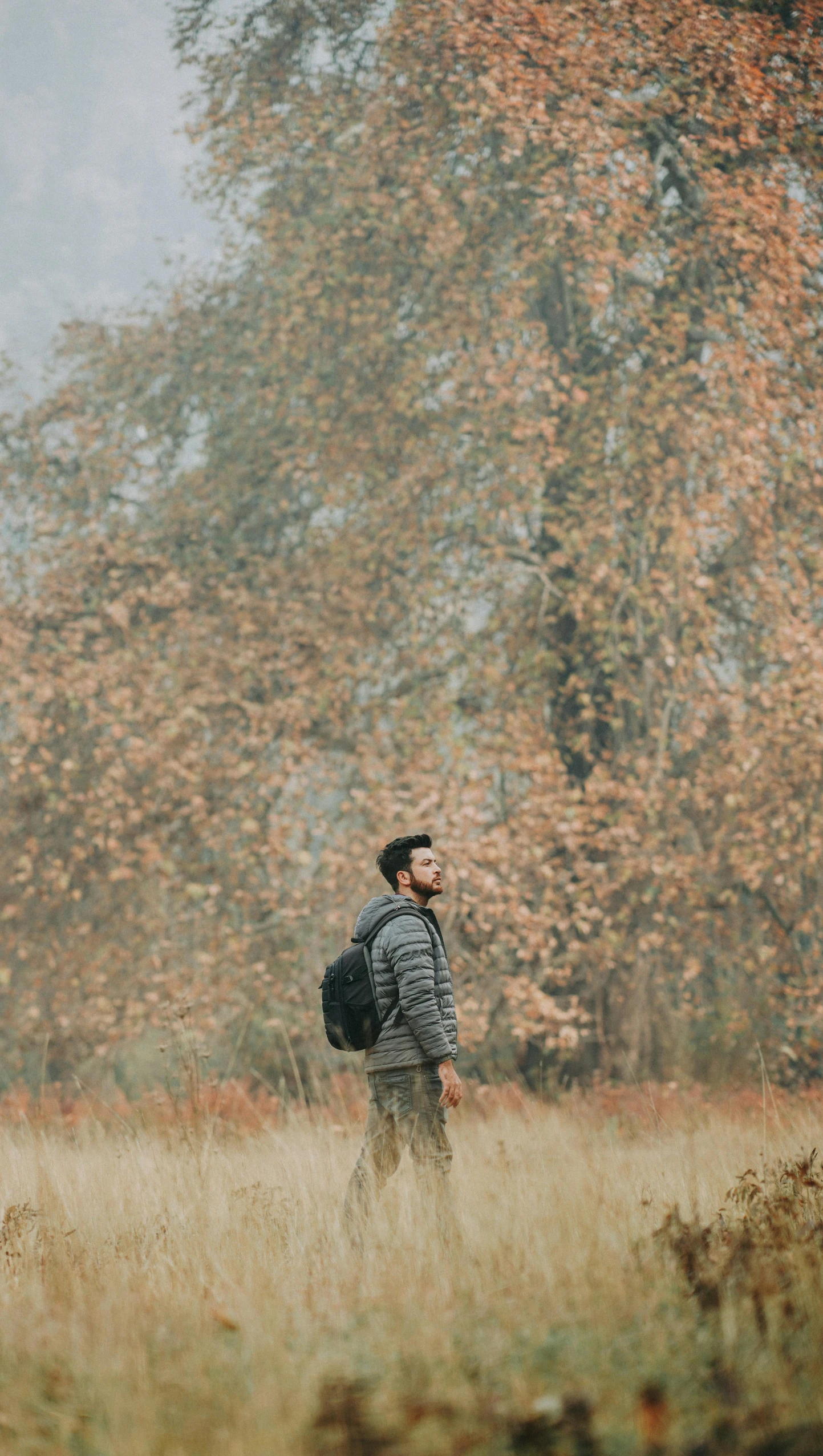 a man standing in an open field while looking into the distance