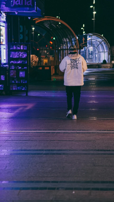 man walking across a street at night with a bag on his back