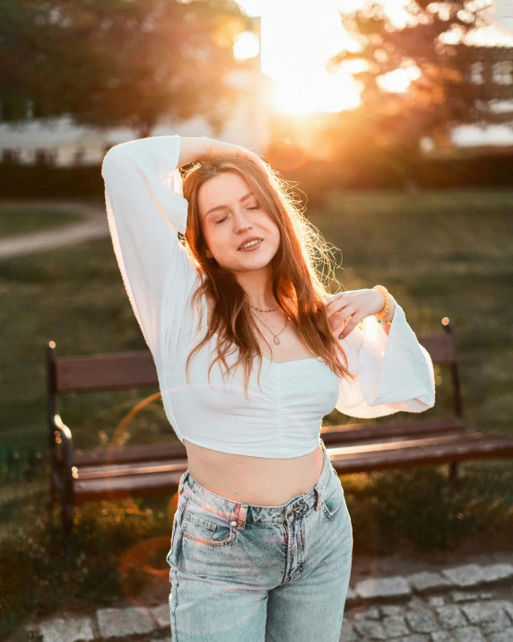 a young lady posing by a park bench in the sun