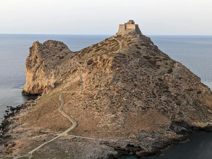 a tall rock cliff sitting on the ocean near the shore