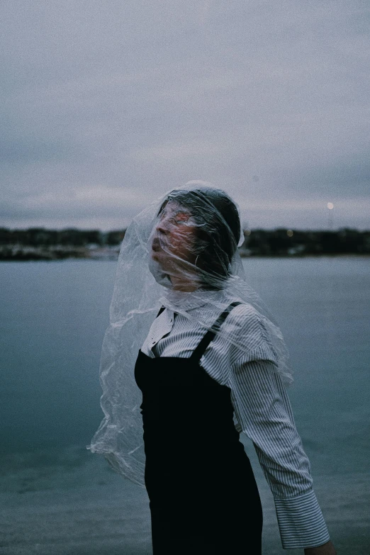 the woman is standing by the water wearing her veil