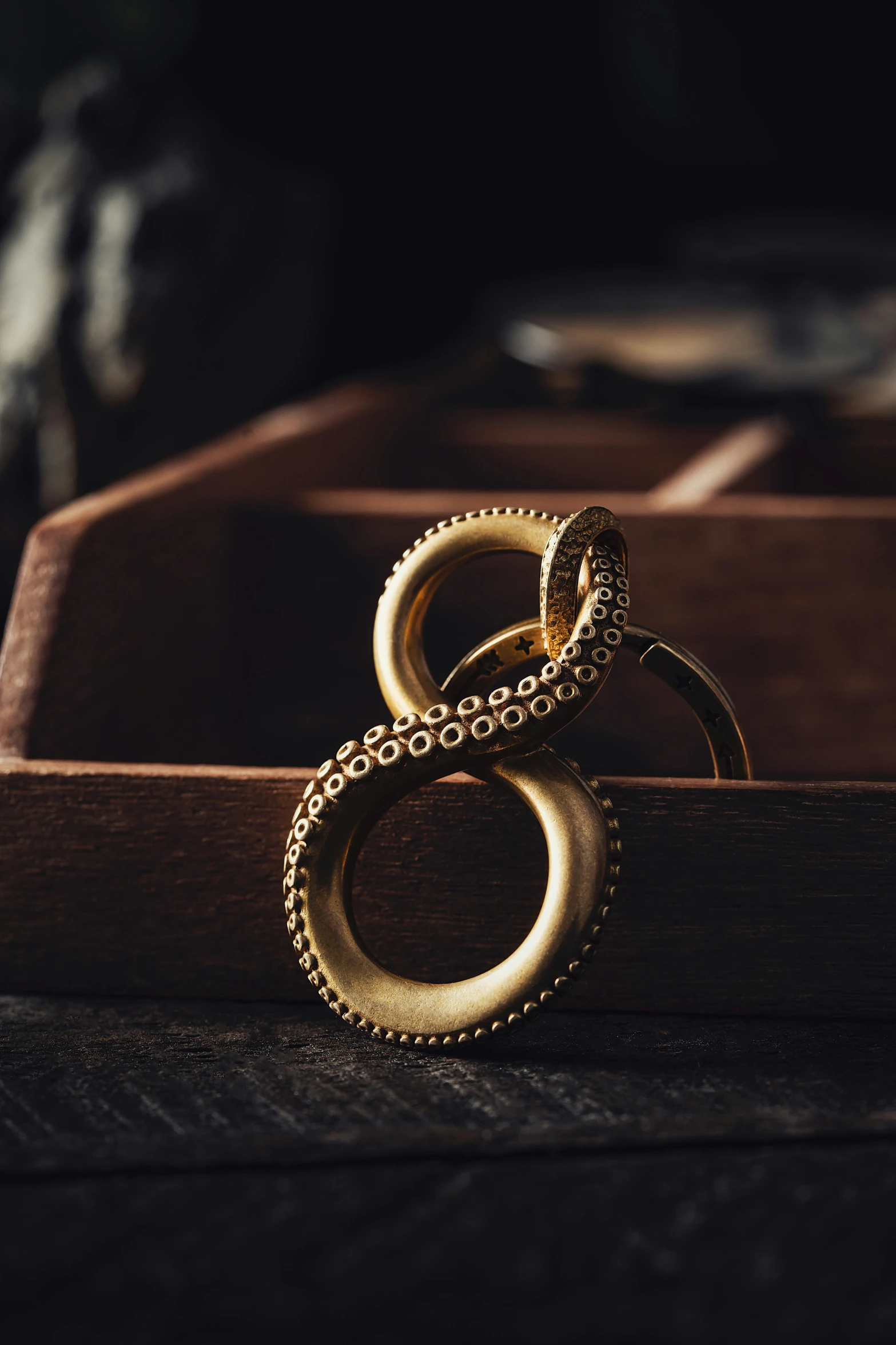 two gold rings sitting inside of a wooden box