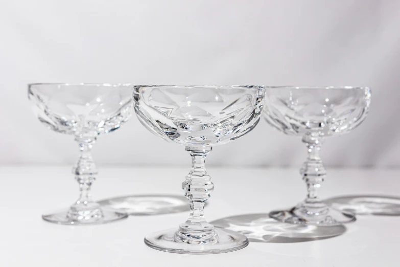 a row of crystal goblets sit on a white table