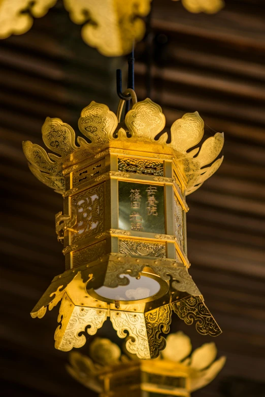 a lantern ornament with lit up golden leaves hanging from it