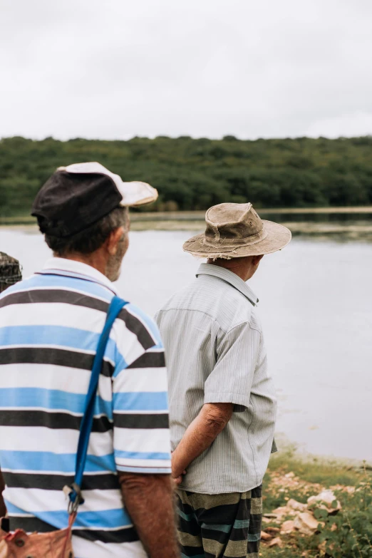 two men standing near a lake looking towards another man