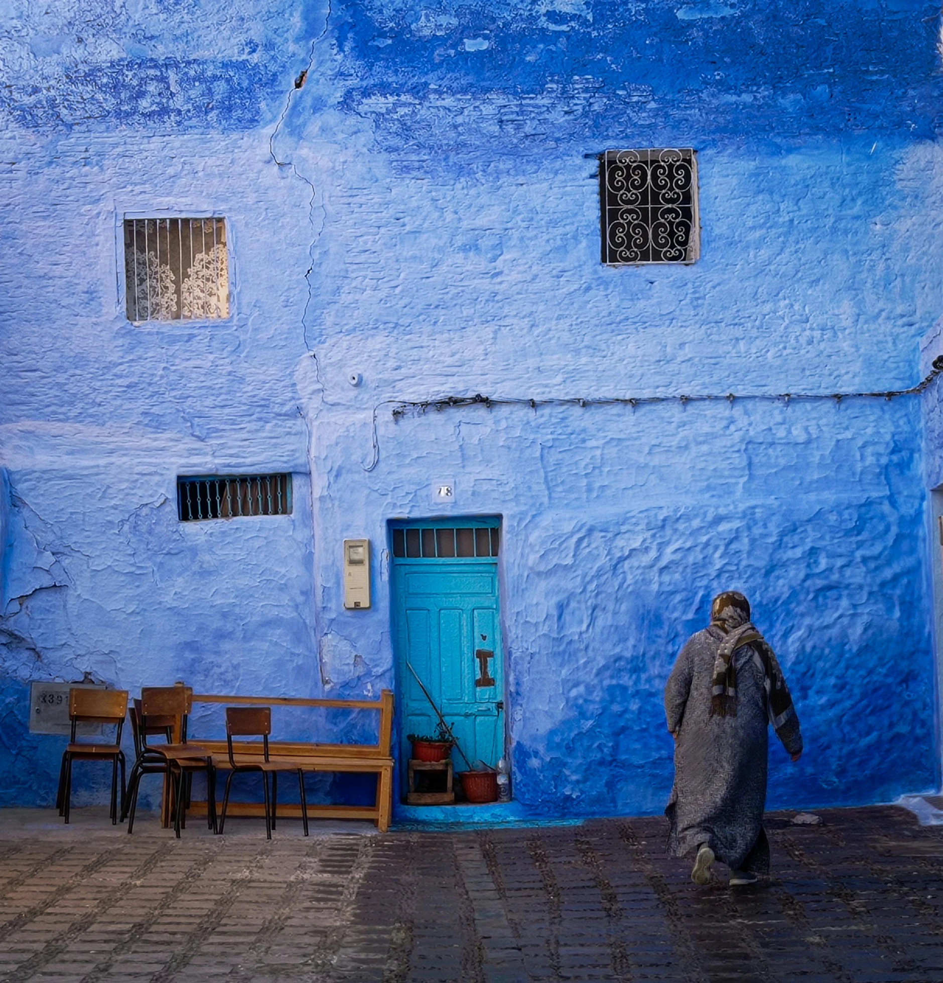 a person wearing a suit stands near a blue wall