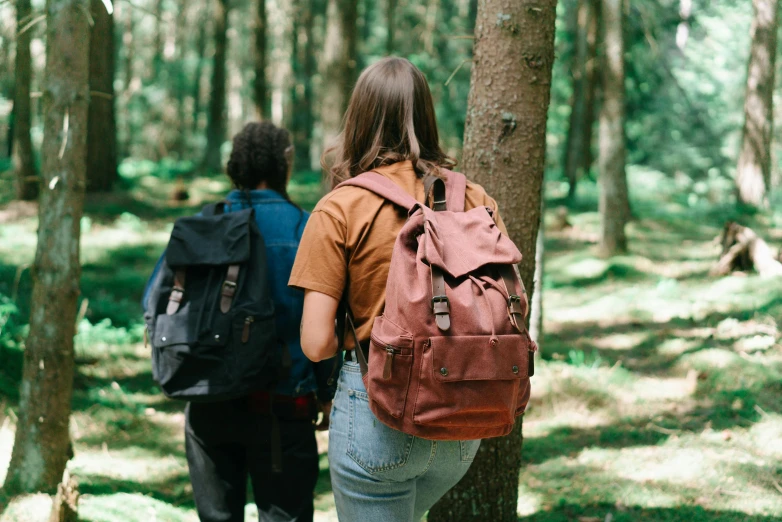 a woman with backpacks is walking in a forest