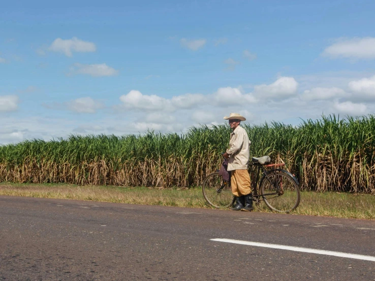 a man walking down the street by a bicycle with a basket