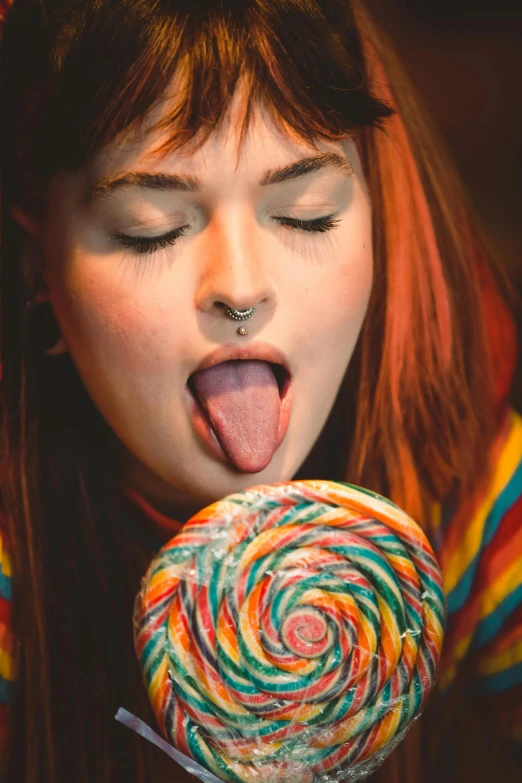 a young woman sticking her tongue out to chew on a large candy