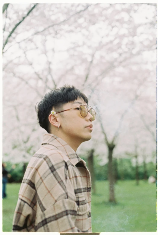 the young man is wearing glasses near the flowering tree