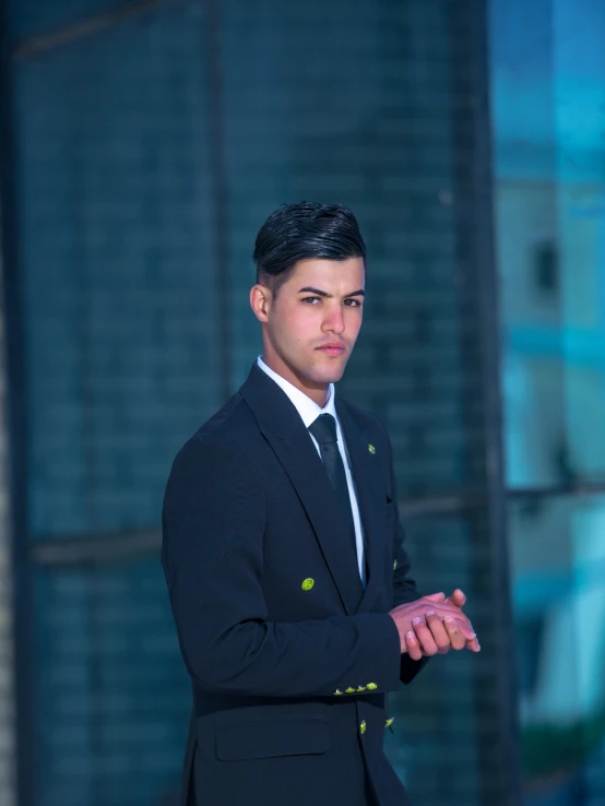 a man with his hand on his chest wearing a dark suit and tie