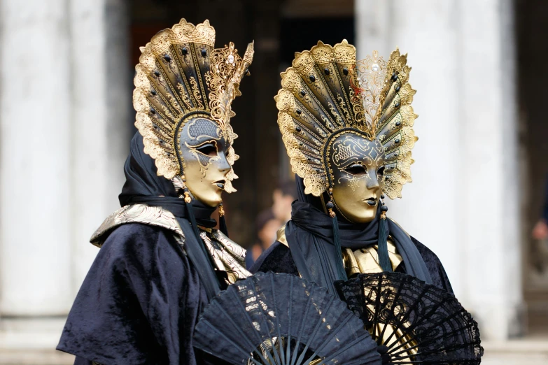 two masked figures standing near each other holding an umbrella