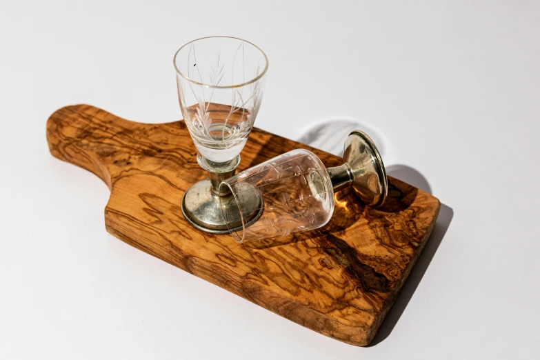 two glass tumblers sitting on top of a wooden board