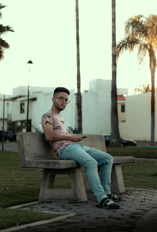 a man sitting on a wooden bench with palm trees in the background