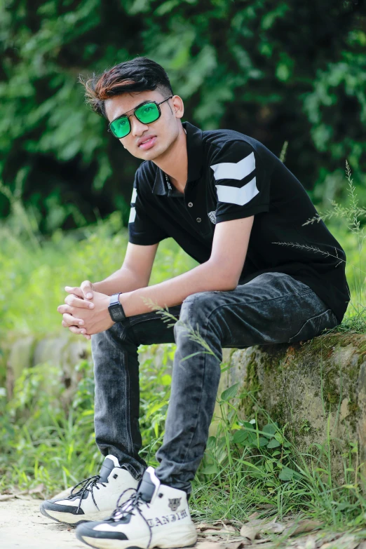 young man sitting in grass with sunglasses on his head