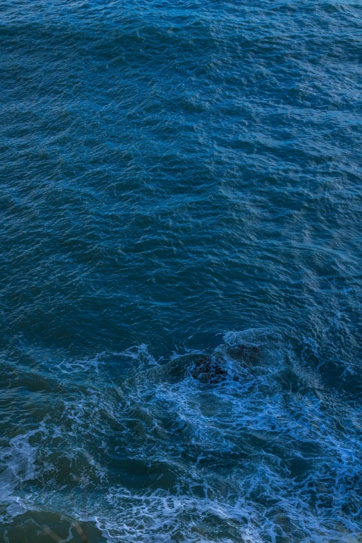 an ocean with blue and white waves and an umbrella floating on top