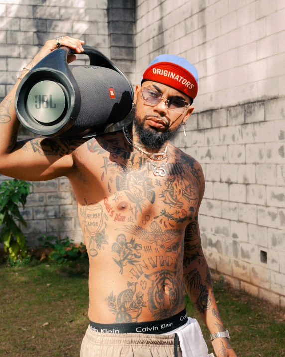 a man with a tattooed arm is holding his speaker