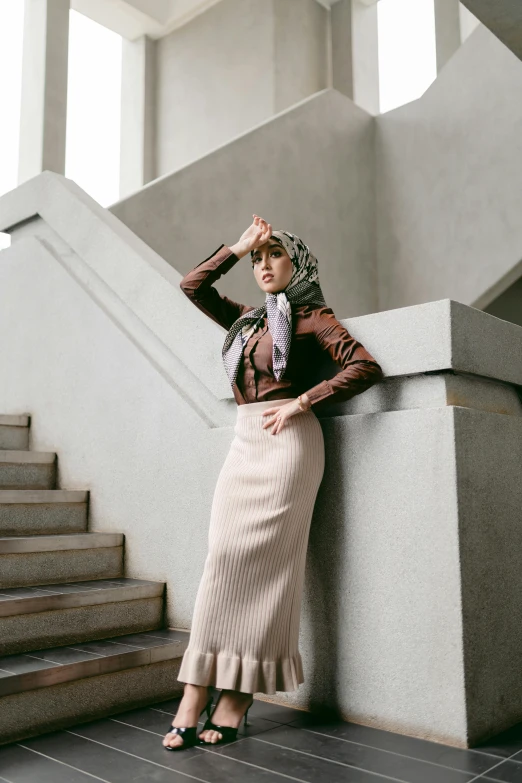 a woman wearing a scarf stands by some stairs