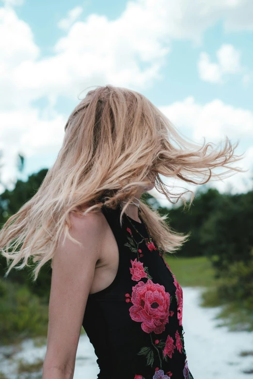 a woman with long hair in a floral dress looking down