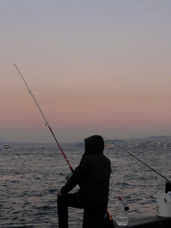 a man is fishing while sitting on a dock