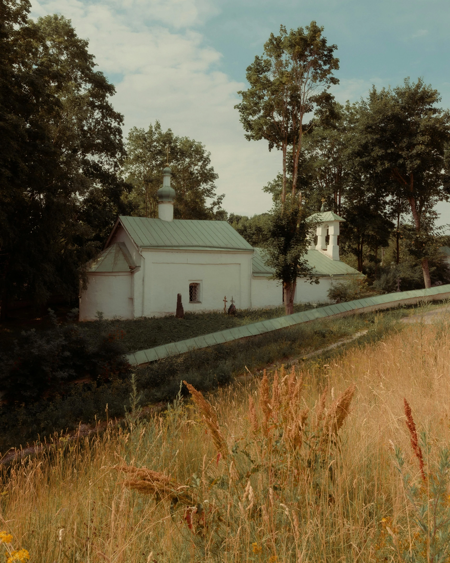 an old white house in a field with lots of grass