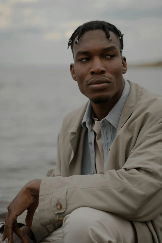 man in trench coat posing for po with ocean behind him