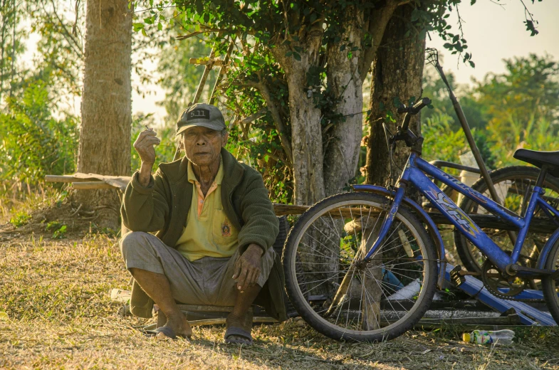 a man kneeling down next to a pile of bicycles