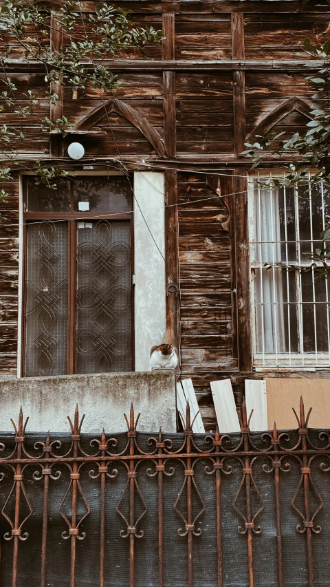 a rusted iron fence sitting next to a building with a closed door