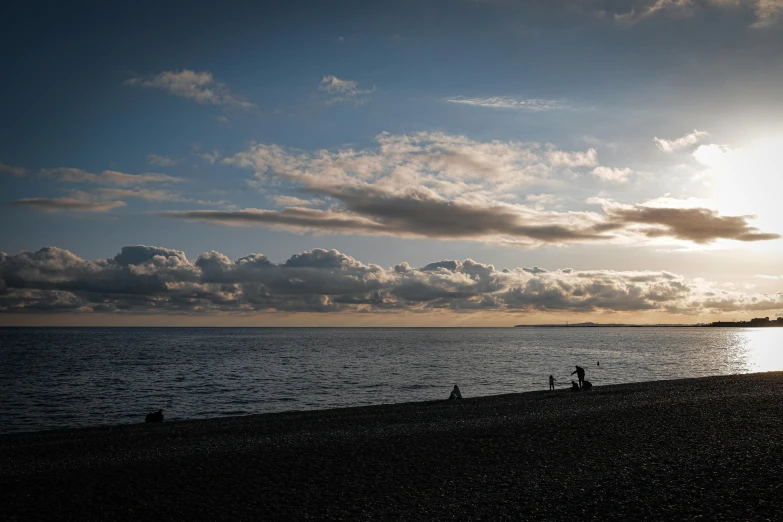 people walking down the beach under the sun