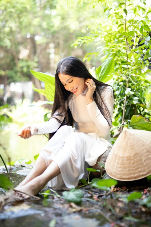 a woman in white is sitting on the rocks near water