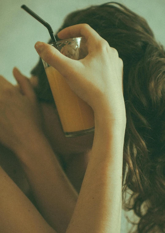a woman is drinking from a glass and holding the bottle