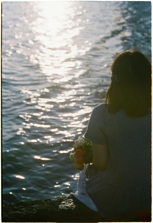 a woman sitting on the edge of the water eating