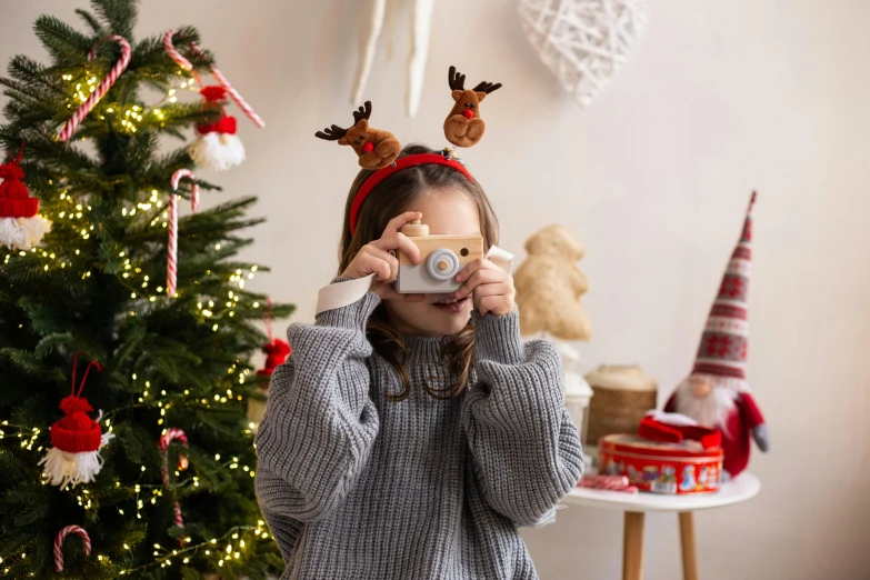  taking picture with camera while holiday decorations are around her