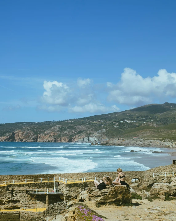 a bunch of people are sitting on rocks by the ocean