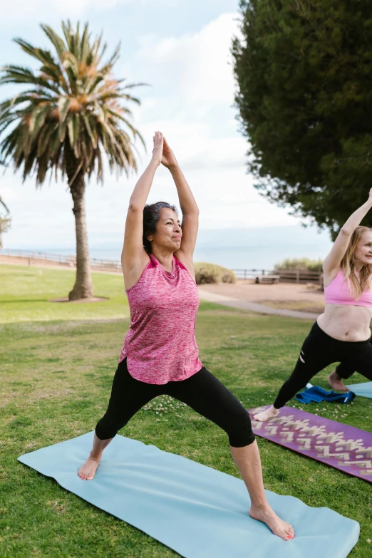 two women practicing yoga on a green field