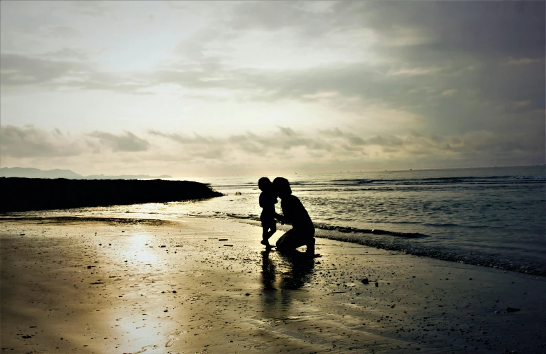an image of mother and baby playing at the beach