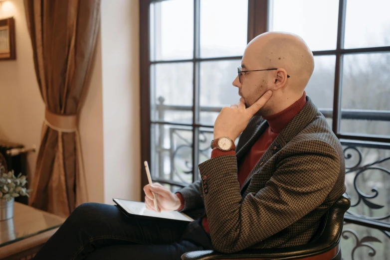 a bald man with glasses sits and talks on the phone