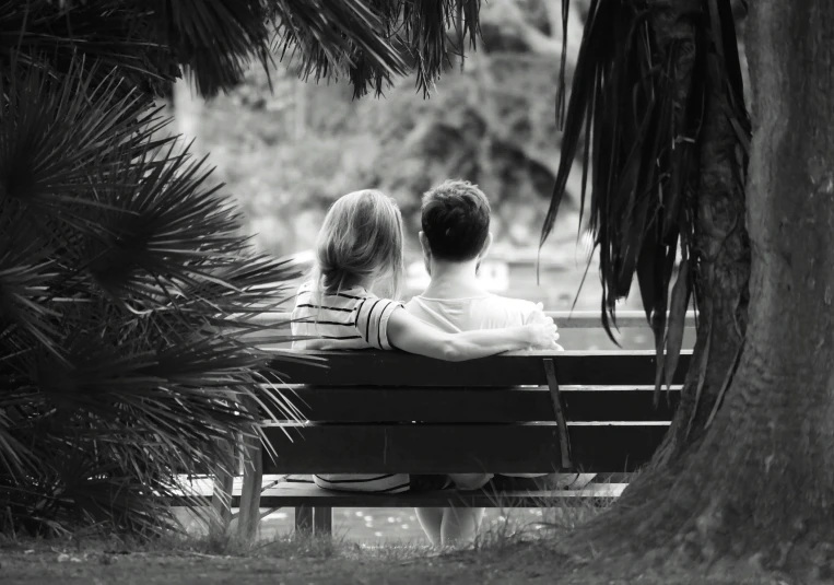 the two people are sitting on the park bench