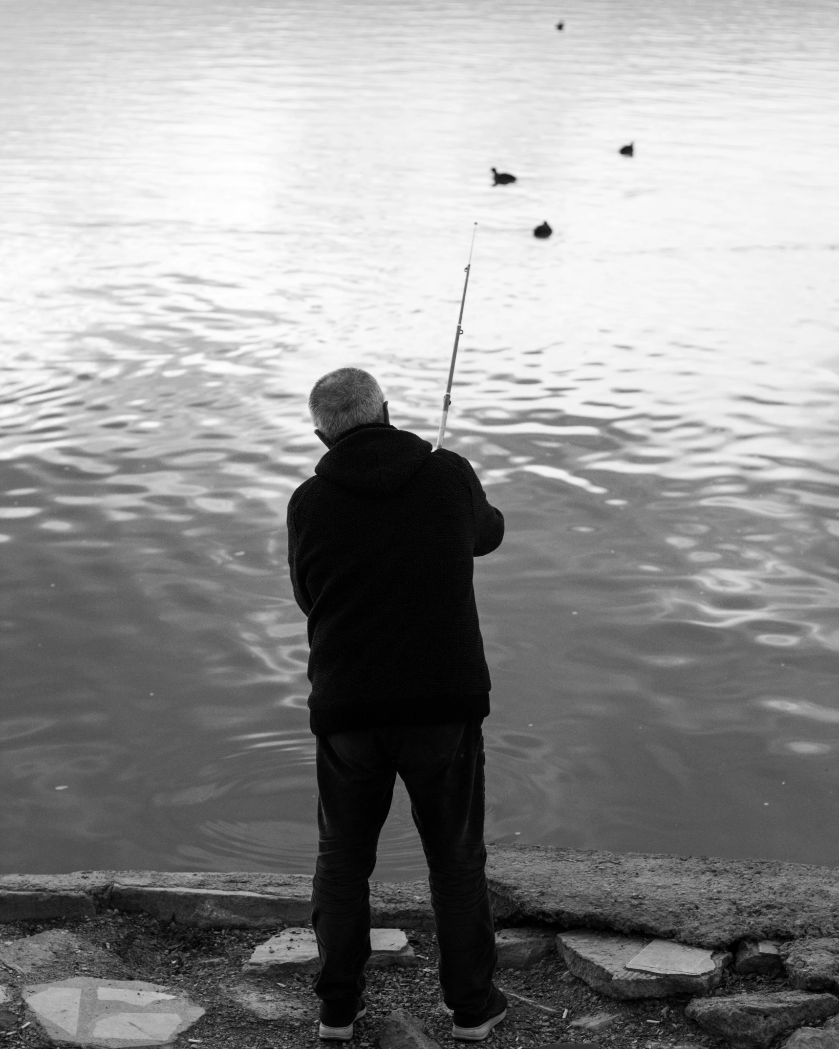 black and white po of a man fishing in the water