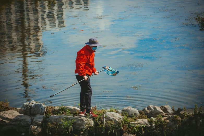 a man standing next to the lake holding a fish