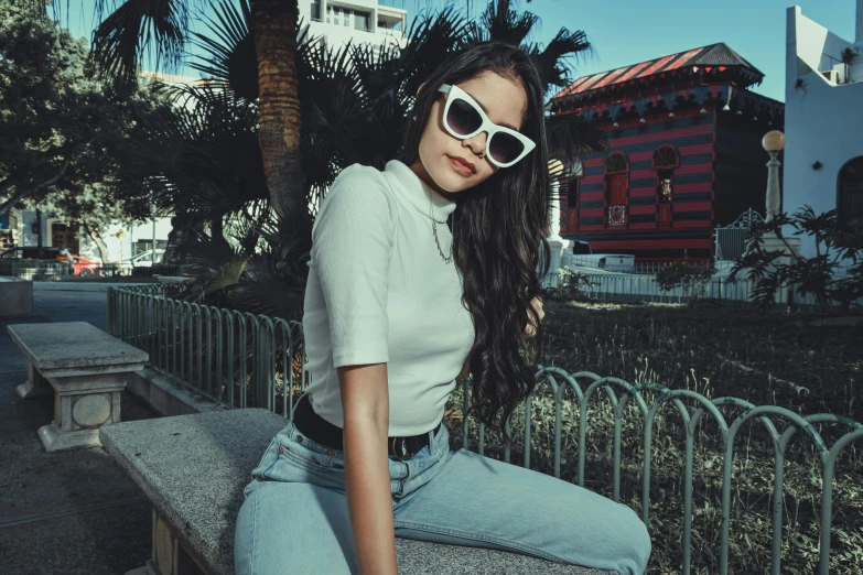 a girl with some sunglasses sitting on a ledge