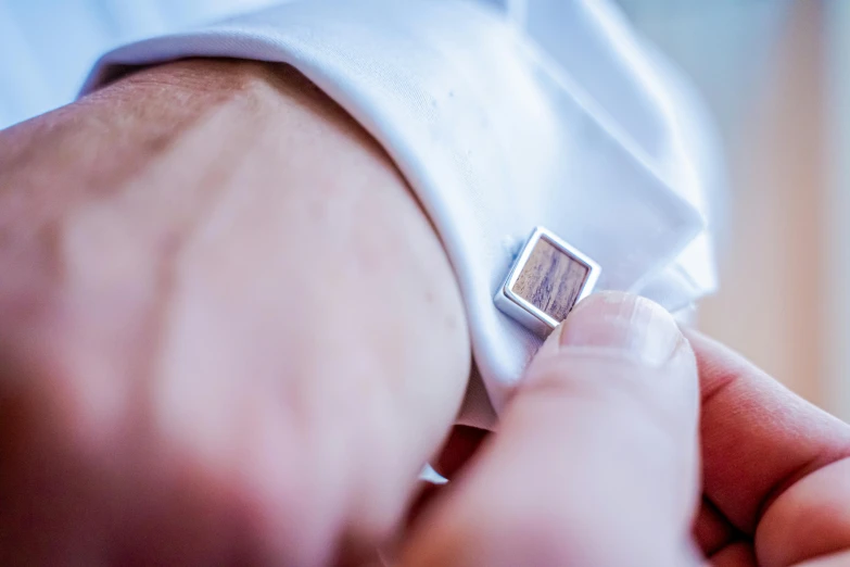 person adjusting the tie on a mans cuff