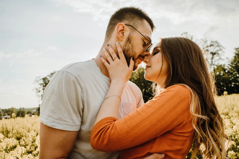 a man and woman kiss each other in a field of flowers