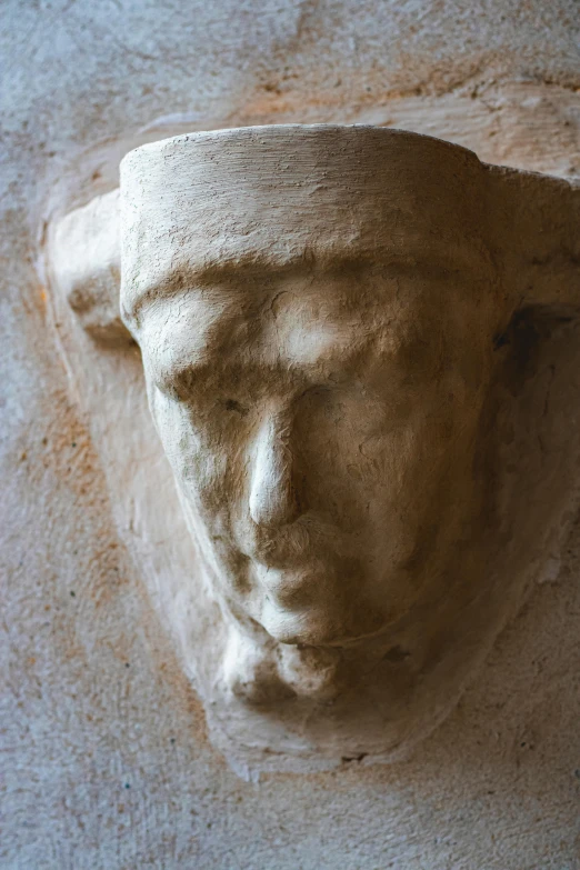 a statue head on a stone wall