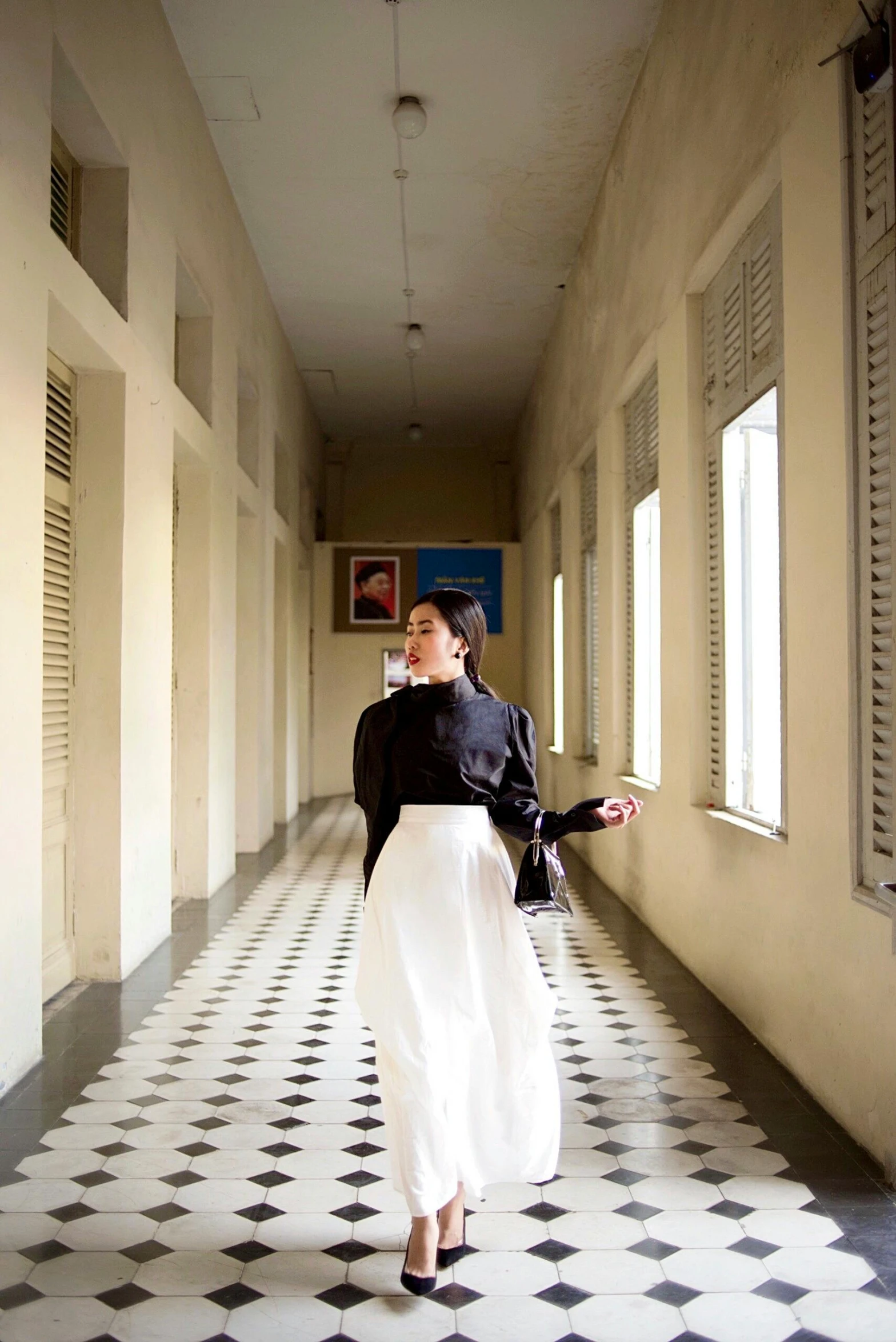 a woman walking down a hallway wearing a skirt